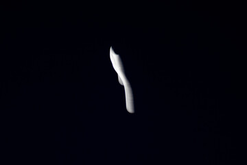 Crescent moon with elongated motion blur in black sky