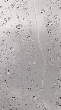 Glass wet background, raindrops overlay on window, rainy day, background drops of rainwater on glass transparent. Raindrops dripping down glass. Water drops flowing on glass. Blurred vertical footage.