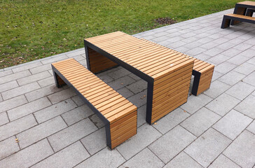 Empty modern sandy brown wooden benches and table in the urban park on tiles on the ground side view