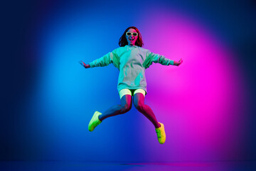 Full length photo of adorable lovely girl wear green hoodie jumping high isolated pink light color background