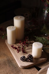 White candles with holiday greenery, creating a festive and peaceful winter ambiance