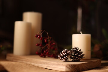 White candles with holiday greenery, creating a festive and peaceful winter ambiance