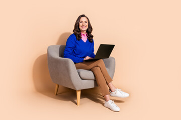 Photo of gorgeous positive successful woman wear blue trendy clothes sit office armchair isolated on beige color background