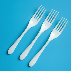 A simple and clean image featuring three white plastic forks arranged in a row on a vibrant blue background, emphasizing modern minimalism and everyday objects.