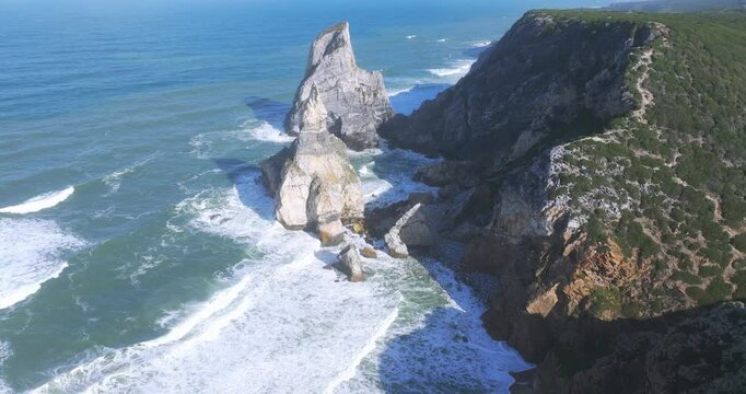 Stunning aerial perspective of Praia da Ursa, Portugal, with bright morning sunlight over the Atlantic coast.