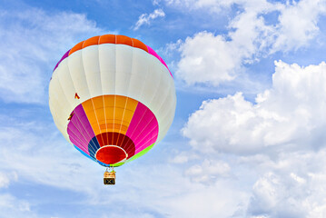 Colorful hot air balloon flying over blue sky with white clouds	