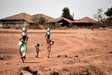 Women carrying pots of water from well, India