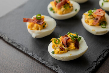 deviled eggs topped with crispy bacon and green onion, creating a savory and colorful appetizer. Perfect for party starters, gatherings, or holiday platters