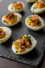  deviled eggs topped with crispy bacon and green onion, creating a savory and colorful appetizer. Perfect for party starters, gatherings, or holiday platters