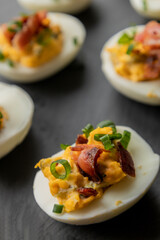  deviled eggs topped with crispy bacon and green onion, creating a savory and colorful appetizer. Perfect for party starters, gatherings, or holiday platters