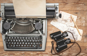 Old antique manual typewriter on the table of the writer with paper with the binoculars and postal cards.