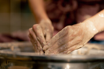 close up the clay modeling studio young girl hands giving shape to clay on a potter's wheel applied art clayware old craftsmanship teacher helps