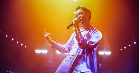Asian RnB Artist Delivering a Grand Performance in a Packed Concert Arena. Singer Dancing Together with Female Backup Dancers. Young Music Fans Enjoying Nightlife Entertainment