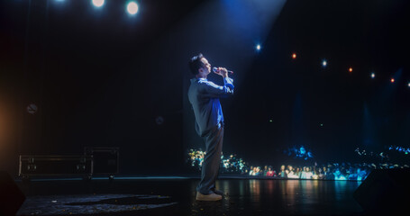 Portrait of a Male Pop Artist Performing Passionately on Stage with Low Key Lighting. Singer with...