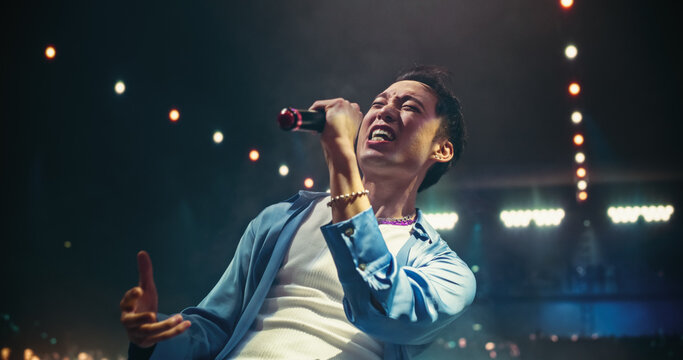 Pop Concert with a Romantic Atmosphere: Young Talented Musician Performing Live on Stage in Front of Screen with Pink Visual Effects. Creative Cinematic Footage with Singer's Silhouette