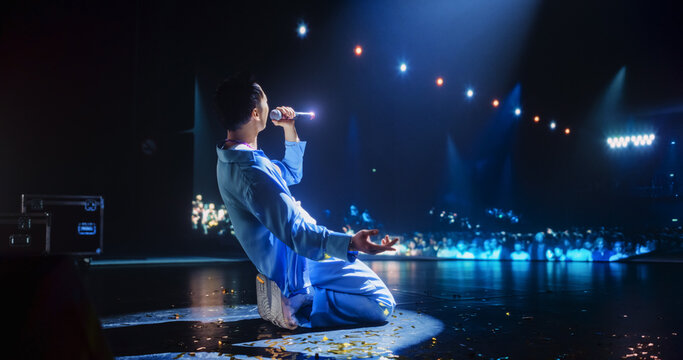 Pop Artist Performing Live Concert on Stage, Illuminated by a Spotlight. Epic Cinematic Performance Captures Artist's Passion and Energy. Dark Background Creating a Dramatic Lonely Scene