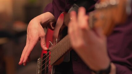 A Man’s Hands Playing a Bass Guitar in a Bar - Rack focus