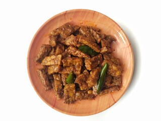 Oreg tempe or Indonesian food made from tempeh with soy sauce and spices on plate isolated on white...
