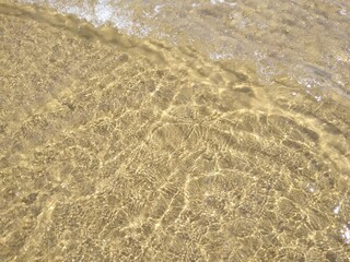 Beutiful Azure sea, slightly wavy water with sunbeams, and sand