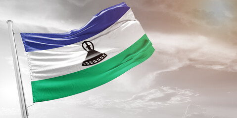 Lesotho national flag cloth fabric waving on beautiful grey Background.