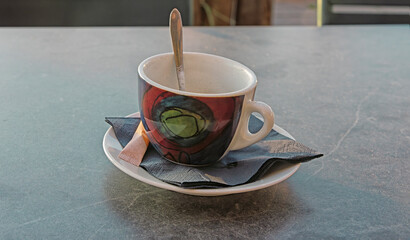 cup and saucer with spoon on a napkin is outside on a table