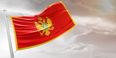 Montenegro national flag cloth fabric waving on beautiful grey Background.