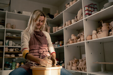 in clay modeling studio young girl hands giving shape to clay on a potter's wheel applied art clayware old craftsmanship mechanical potter's wheel