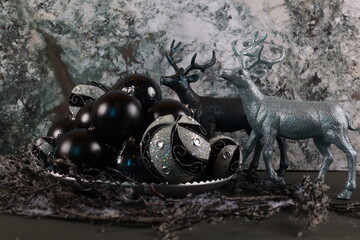 etallic and blue-toned deer figurines surrounded by black and silver Christmas ornaments, set in a winter forest theme.