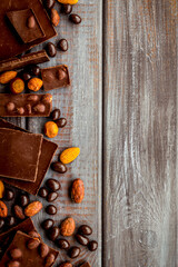 Chocolate with nuts and its ingredients on wooden background top view copyspace