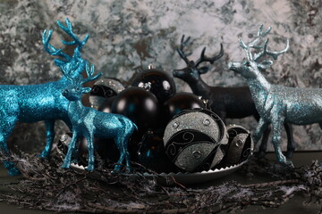 blue and black Christmas ornaments with silver accents, displayed alongside deer figurines.