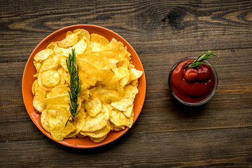 Potato crisps with tomato sauce on wooden background top view