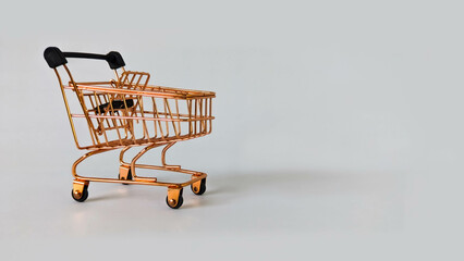 Gold mini shopping trolley on gray background, Concept for shopping template