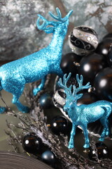 blue and black Christmas ornaments with silver accents, displayed alongside deer figurines.