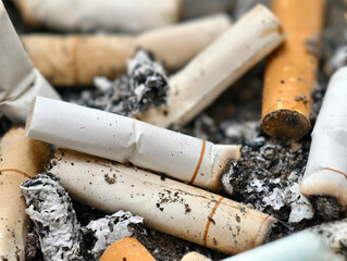 A close-up of numerous cigarette butts, highlighting the health hazards to smokers