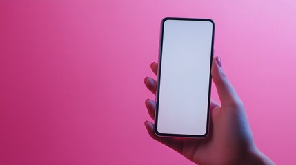 A person holds a smartphone with a blank screen against a vibrant pink background during the evening.
