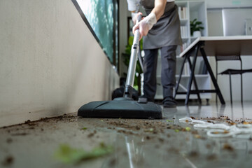 Professional Cleaner Using Vacuum to Remove Dirt from Modern Office Floor with Efficient Cleaning Techniques