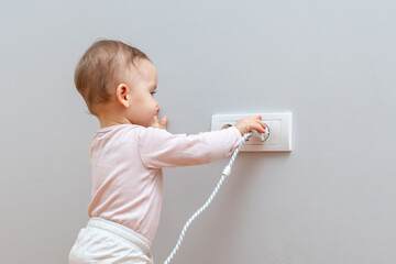 A curious baby explores a plug and outlet, highlighting the importance of childproofing and home safety measures.