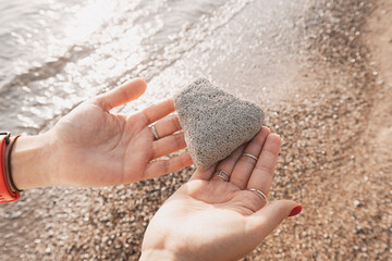 Woman holding pumice stone on beach at sunset