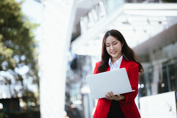 Stylish Asian businesswoman standing outdoors and confidently using tablet to plan finances and find digital solutions.