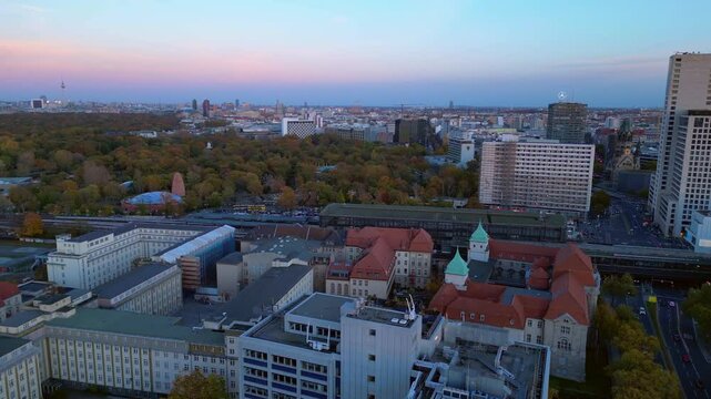 zoologischer garten train station and surrounding urban landscape in berlin, germany during sunset. Dramatic aerial view flight ascending drone