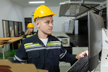 Man paper warehouse worker check quality and quantity cardboard corrugated carton in storage stock product with computer system . Large industry in paper production line.