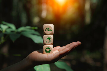 energy renewable, net zero icon at wood box on hand  at green nature blur background. Net zero...