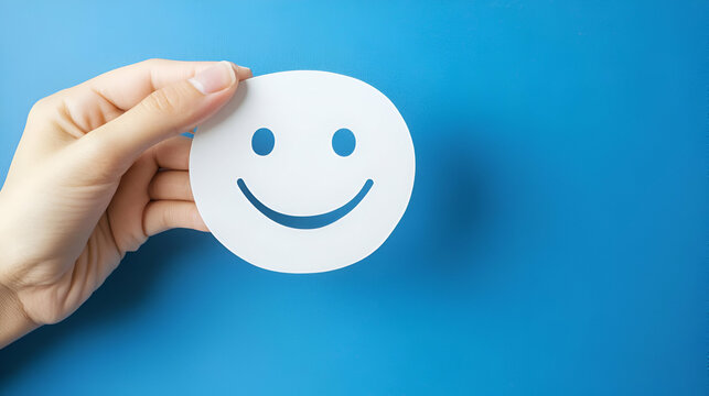 Paper-Cut Smile Face Held by Hand on a Blue Background, Perfect for Text Insertion