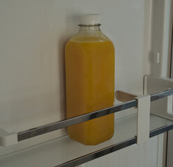 A bottle of fresh squeezed orange juice on a fridge door