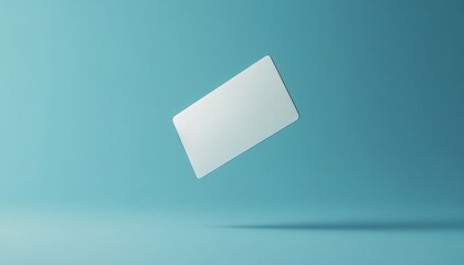 Floating empty white credit card on light blue background with natural lighting and sharp focus