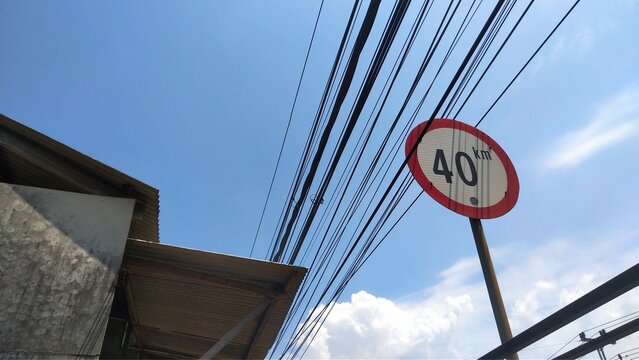 Speed limit sign under sunny day with clear blue sky and cable line