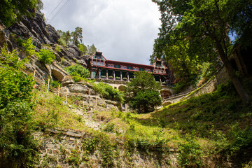 historical architectural building among rocky mountains with green trees under blue sky