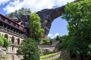 historical architectural building among rocky mountains with green trees under blue sky