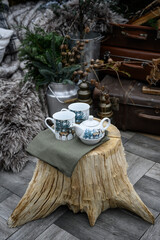 Christmas decoration on wooden table. Tea set on stump. Teapot and cups