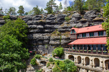 historical architectural building among rocky mountains with green trees under blue sky
